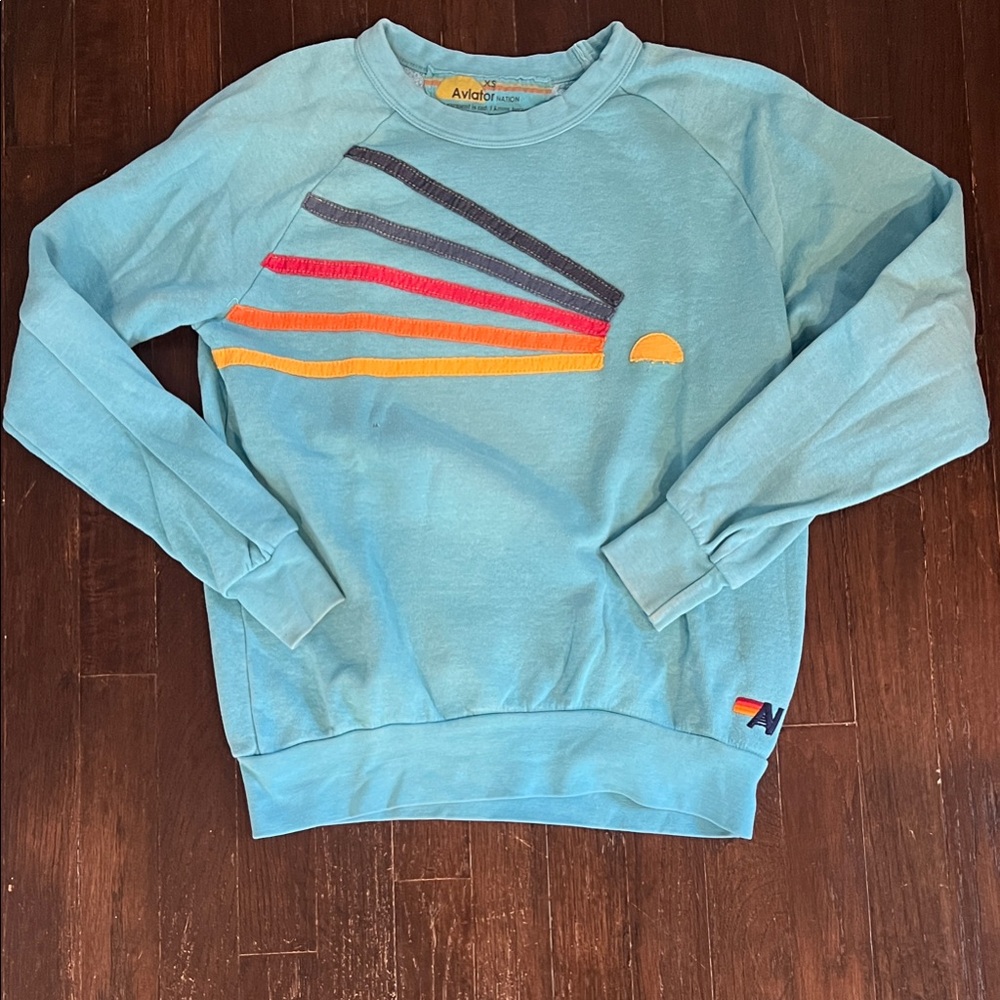 Aviator Nation Blue Sweatshirt with Colorful Stripes and Sun.